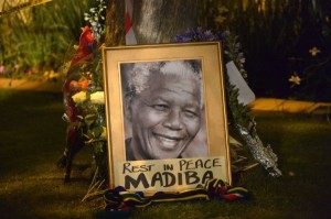 This picture shows a framed image of former South African president Nelson Mandela as people pay tributes following his death, in Johannesburg on December 6, 2013. Nelson Mandela, the revered icon of South Africa's anti-apartheid struggle and a towering figure of 20th century politics, died on December 5 aged 95.  AFP PHOTO / ALEXANDER JOE